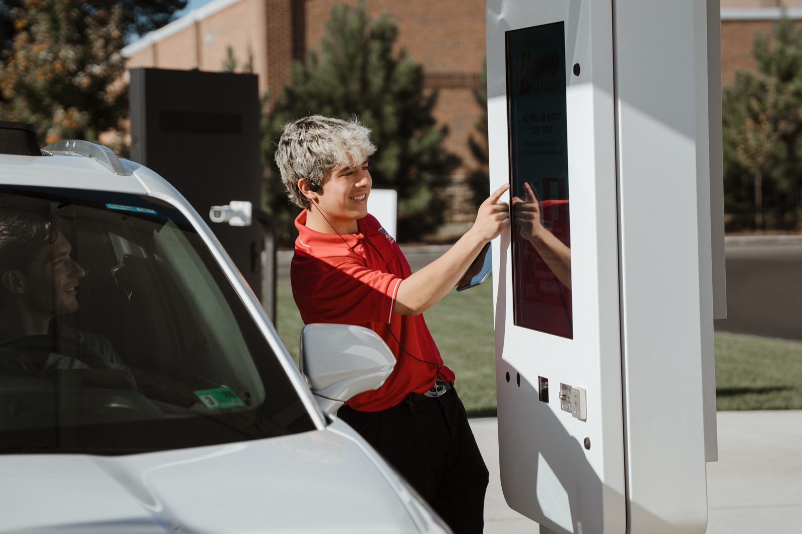 An attendant helping a member pay at a wash kiosk